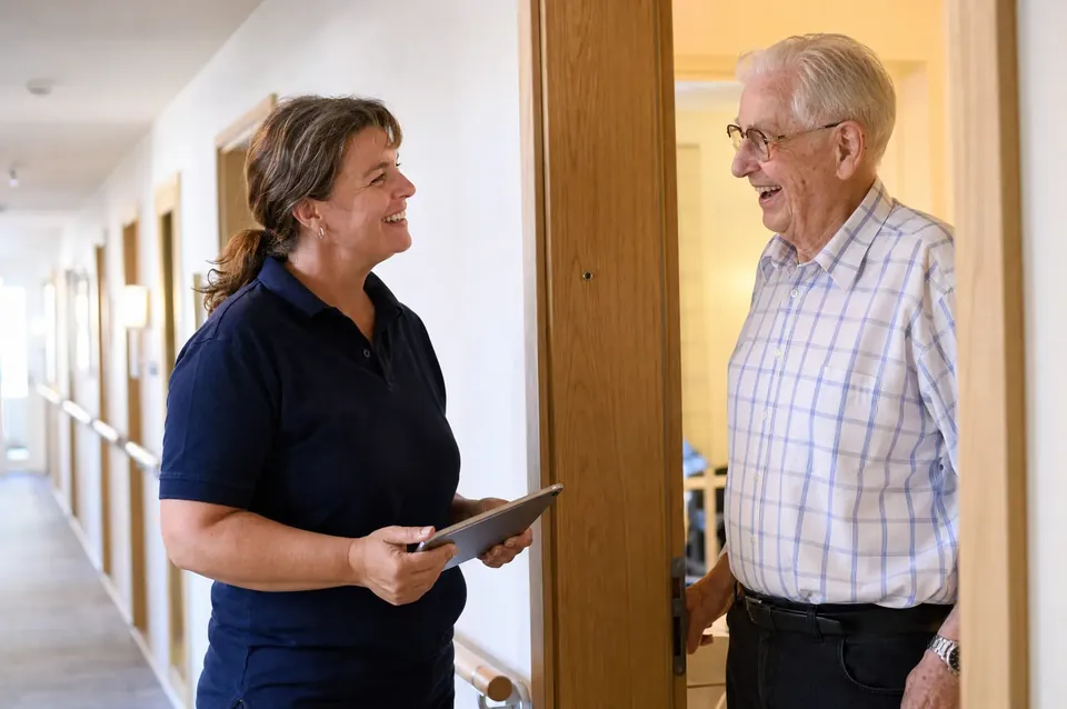 Ansprechpartnerin im Gespräch mit einem Bewohner an der Wohnungstür